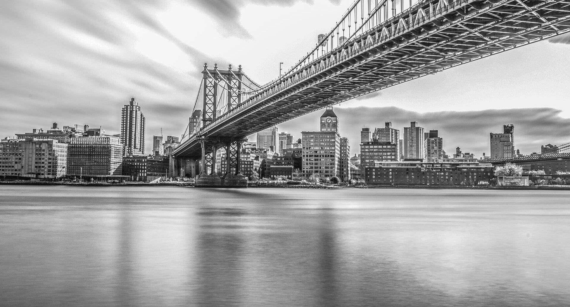 bridge over a river into NYC in black and white